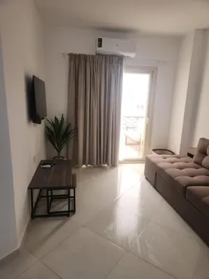 a living room with a couch and a table and a television at Arabian Suites by Imperial 1 bed Apartment in Hurghada