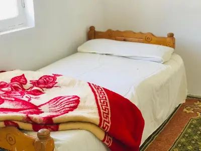 a bed with a red and white blanket on it at ISIS Hostel in Aswan
