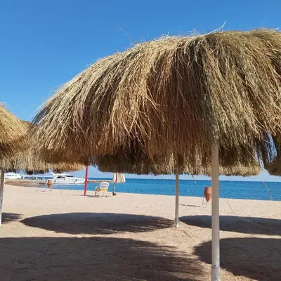 a straw umbrella on a beach with the ocean at Princess Resort, Hurghada in Hurghada