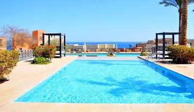 a large blue swimming pool with the ocean in the background at Azzura Sahl Hasheesh in Hurghada