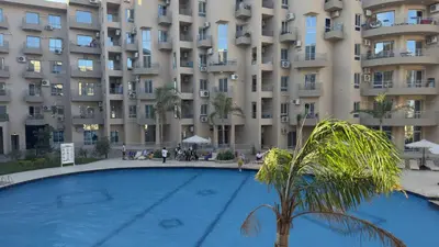 a large apartment building with a palm tree in front of it at El princess one bedroom hurghada in Hurghada