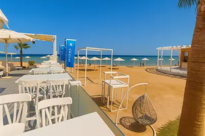 a beach bar with white tables and chairs and the beach at Selena Bay Prime Stays in Hurghada