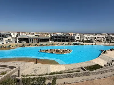 a large blue swimming pool with buildings in the background at Makadi Heights Resort in Hurghada