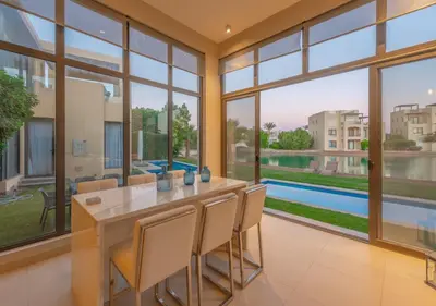 a dining room with a table and chairs and large windows at Airy & Bright 4BR Villa in Tawila, El Gouna, Private Pool & Lagoon Access in Hurghada