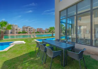 a patio with a table and chairs next to a pool at Airy & Bright 4BR Villa in Tawila, El Gouna, Private Pool & Lagoon Access in Hurghada