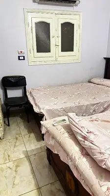 two beds in a room with a chair and a window at Diebo in Aswan