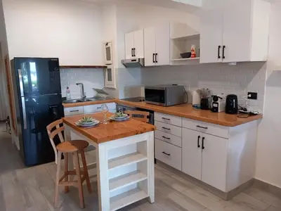 a kitchen with white cabinets and a wooden counter top at Peaceful & bright lagoon escape - Shared infinity Pool - 1BR - Sabina, El Gouna in Hurghada