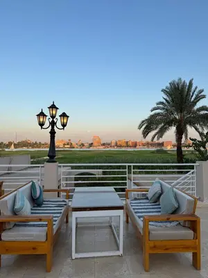a patio with chairs and tables and a street light at Royal Nile Villa - Luxury Nile Sky Penthouse 2 in Al Aqālitah