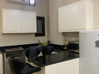 a kitchen with black counter chairs and white cabinets at One-Bedroom Chalet at Turtles Beach Resort , Pool & Side Sea View C22 in Hurghada