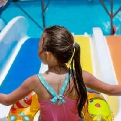 a young girl in a bathing suit standing next to a slide at Mirage Bay Resort Aquapark SAM Suite in Hurghada