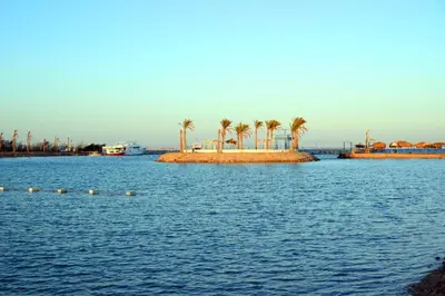a large body of water with palm trees on an island at Mirage Bay Resort Aquapark SAM Suite in Hurghada