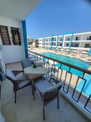 a balcony with a table and chairs and a swimming pool at Mirage Bay Resort Aquapark SAM Suite in Hurghada
