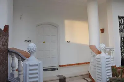 a hallway with a white door and white pillars at White Villa in Luxor