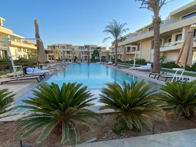 a large swimming pool with palm trees in a resort at Chic G Cribs Studio in El Gouna