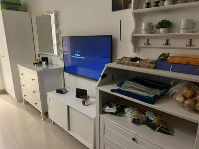 a living room with a tv and white shelves at Chic G Cribs Studio in El Gouna
