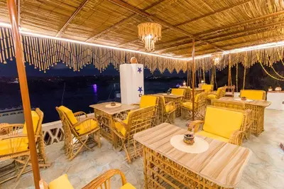 a restaurant with tables and chairs and a view of the water at Casa Nile View rooms - Nubian House -by kerma hospitality in Aswan