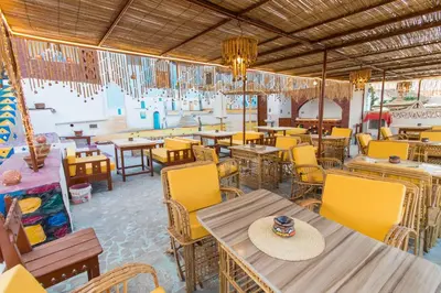 a restaurant with yellow chairs and tables and tables at Casa Nile View rooms - Nubian House -by kerma hospitality in Aswan