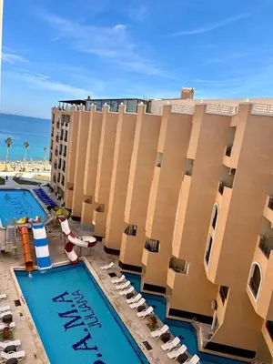 a hotel with two pools and chairs and the ocean at Large Studio Beach & Pool Hurghada - Wifi in Hurghada