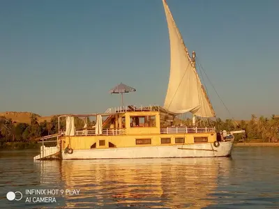 a boat with an umbrella on the water at King Arthur luxury Dahabyaa in Luxor