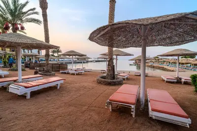 a beach with benches and umbrellas on the beach at Geisum beach hotel in Hurghada