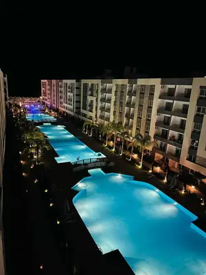 a row of swimming pools at night with buildings at Fanadir Bay in Hurghada