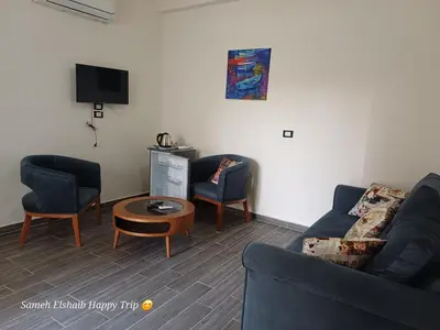 a living room with two chairs and a couch and a tv at Suncare America Resort - luxury rooms in Hurghada