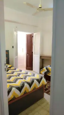 a bedroom with a bed with a yellow and black comforter at Atlas Aswan Apartment Near Nile Corniche and Old Tourist Market شقة أطلس أسوان بجوار كورنيش النيل والسوق السياحي القديم in Aswan