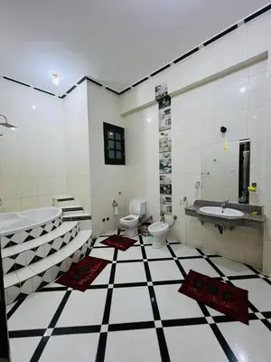 a bathroom with a black and white tiled floor at Luxor Adventure Guest House in Al Aqālitah