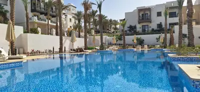 a large swimming pool with palm trees and buildings at El Gouna Luxury 1BR Golf Apartment at Ancient Sands Resort Pool, Beach & Marina Access in Hurghada