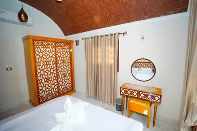 a bedroom with a bed and a table and a mirror at Osman House Luxor in Luxor