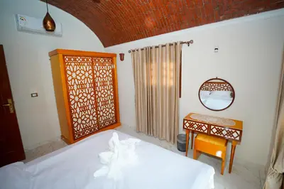 a bedroom with a bed and a table and a mirror at Osman House Luxor in Luxor