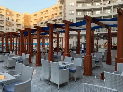 a patio with white chairs and tables and wooden structures at Tiba Golden Resort in Hurghada