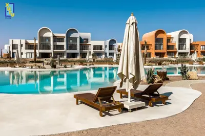 a pool with two lounge chairs and an umbrella and a pool at The 2BDR Blue Horizon Kamaran El Gouna in Hurghada