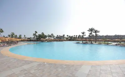 a large swimming pool in a resort with palm trees at Xanadu Club Makadi Bay - High Class All Inclusive in Hurghada