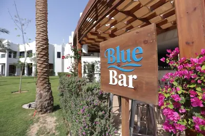 a blue bar sign in front of a building with flowers at Xanadu Club Makadi Bay - High Class All Inclusive in Hurghada