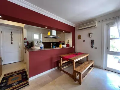 a kitchen with a red wall and a wooden table at Lagoon Charm | 1BR in Steigenberger El Gouna in Hurghada