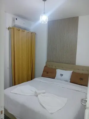 a bedroom with a white bed with a yellow curtain at Aqua Infinity D306 in Hurghada
