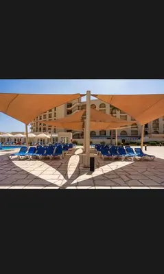 a group of blue lounge chairs and a building at Timeshare for rent at sunny days family resort in Hurghada