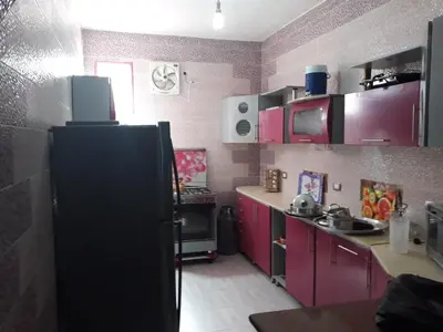 a kitchen with pink cabinets and a black refrigerator at Ashria gest house in Jazīrat Salūjah
