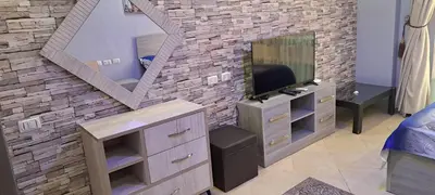 a living room with a tv and a brick wall at Florenza Resort - Roboost - Hurghada in Hurghada