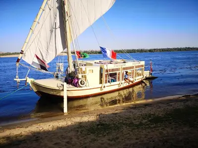 a sail boat is docked on the water at Katadool Boat in Aswan