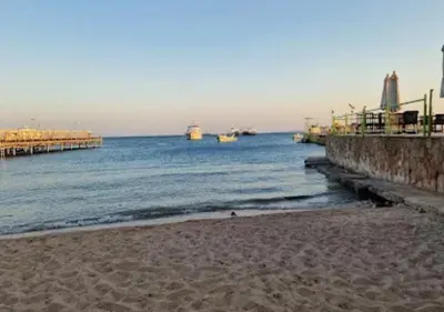 a beach with a pier and boats in the water at Cozy 1BR Pool View Apartment Steps from the Beach in Hurghada