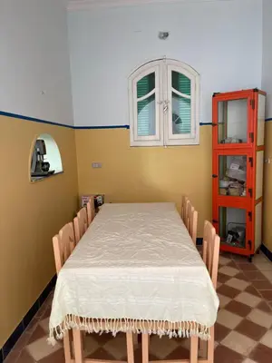 a dining room with a table and chairs and a window at ايـو كـاتو in Jazīrat ‘Awwāḑ