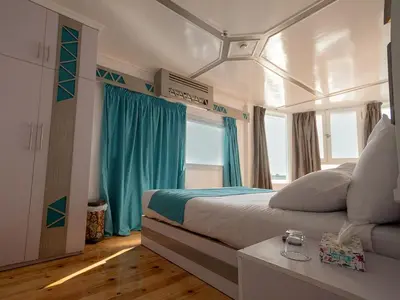 a bedroom with a large bed with blue curtains at Dahabiya Nile Cruise in Luxor