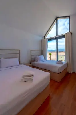 two beds in a room with a large window at Luxury Stays in Wadi Jebal Soma Bay in Hurghada