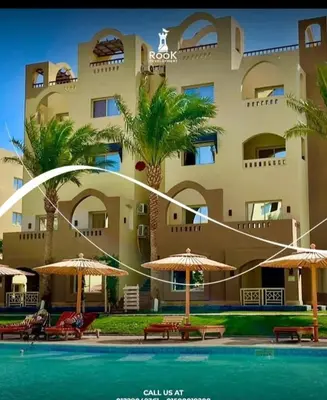 a building with a swimming pool in front of a resort at Karma Aqua Beach in Hurghada