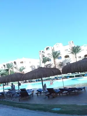 a group of chairs and umbrellas next to a swimming pool at Karma Aqua Beach in Hurghada