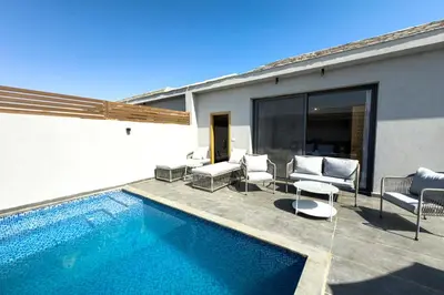 a house with a swimming pool and chairs next to a building at Elegance Serene 3 BDR Townhouse w Private Pool Bali Gouna in Hurghada