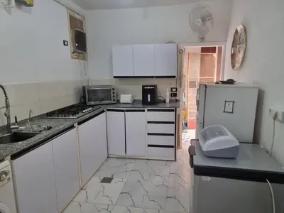 a small kitchen with white cabinets and a refrigerator at Adream partment in Luxor in Luxor