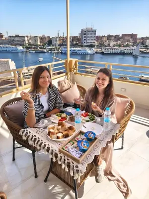 two women sitting at a table with food at Crystala 2 guest house in Aswan
